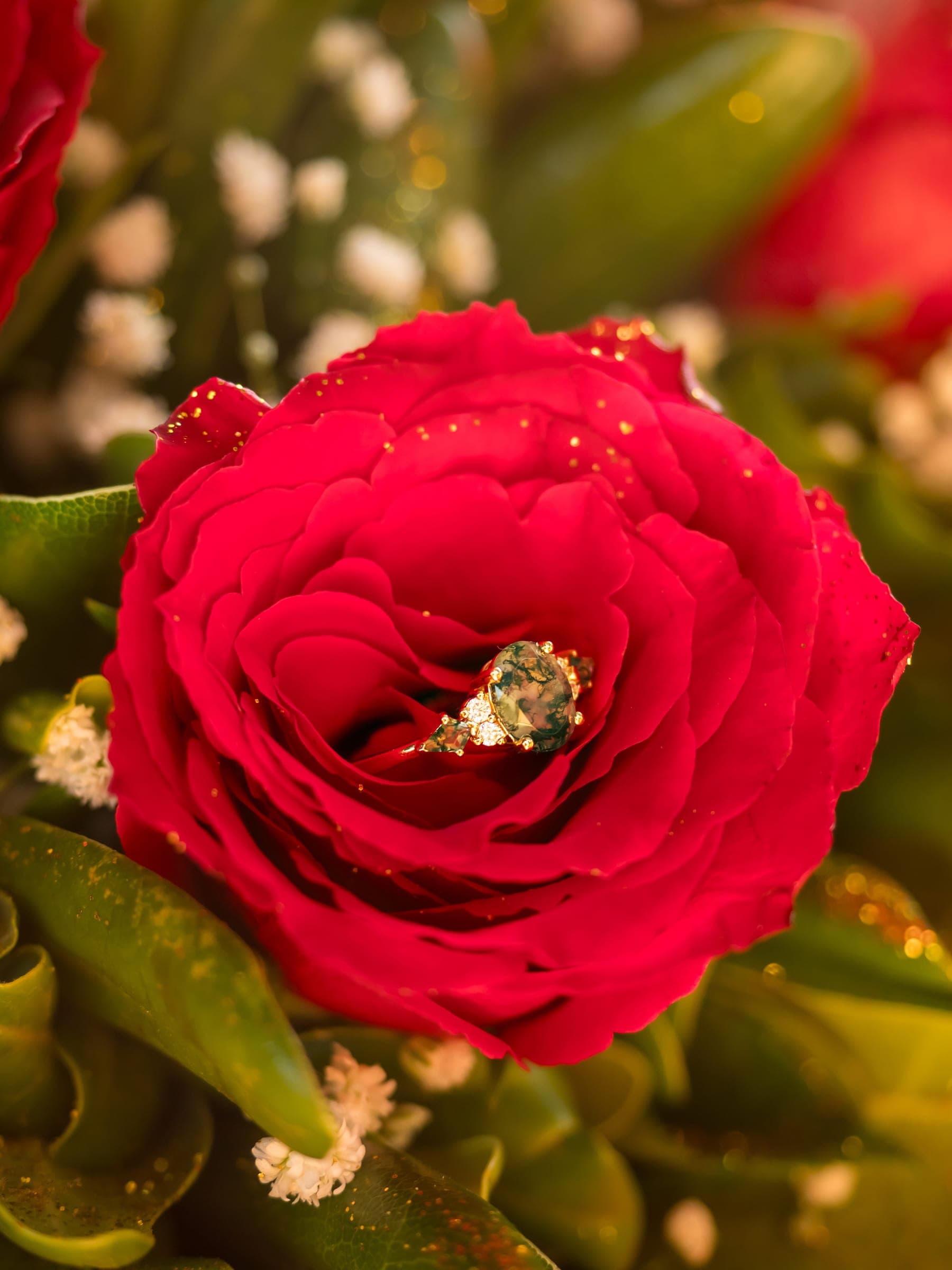 An engagement ring resting inside a red rose